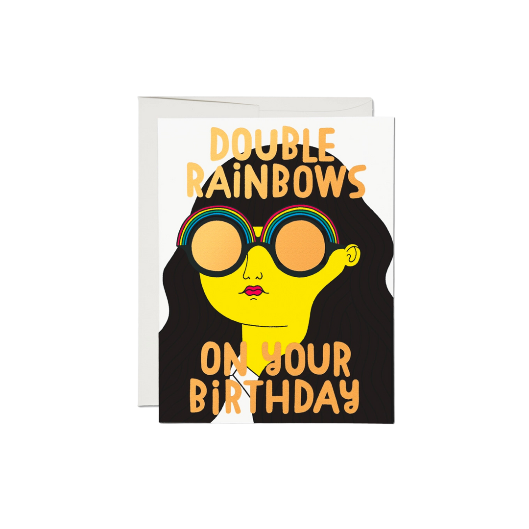 Cartoon woman wearing double rainbow sunglasses, says "Double Rainbows On Your Birthday".This 5.5 x 4.25 inch Double Rainbows Birthday Card is printed on 100lb heavyweight card stock and features a foil stamped, offset printed illustration by Anke Weckmann. It is printed in the USA on recycled paper and is blank inside.