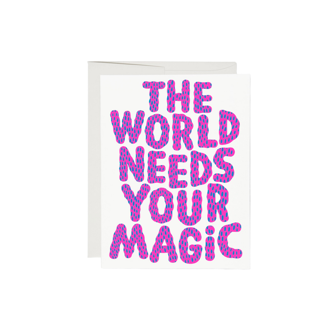 Pink and blue lettering on a white background reading "The World Needs Your Magic". The interior of the card is left blank, while the exterior is 100lb heavyweight card stock, with offset printing. Measuring 5.5 x 4.25 inches, the card features an illustration by Anke Weckmann and is printed in the USA on recycled paper.