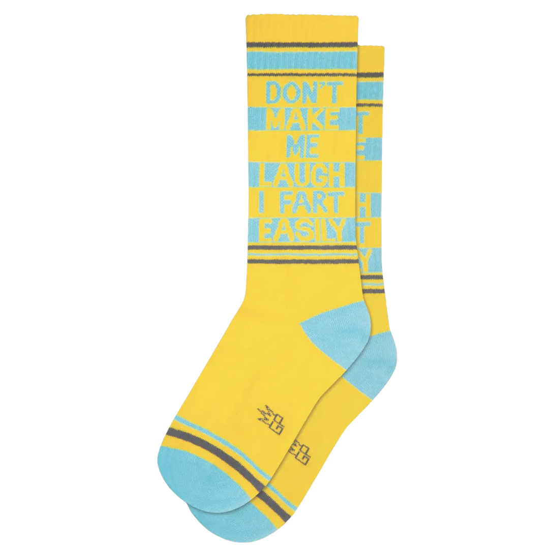 Yellow socks with brown and blue stripes and text reading "Don't Make Me Laugh I Fart Easily". These socks offer 65% cotton, 32% nylon, and 3% spandex for a potentially embarrassing situation 💨 Wear these on your feet and you won't have to worry about being blamed if you let out a toot 😬 Plus, these socks are made in the USA.