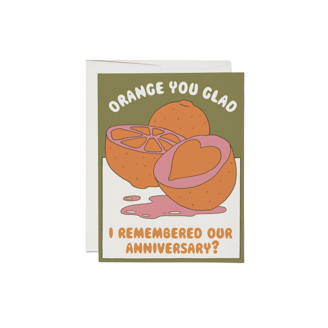 Orange with heart cutout on a green and white background with text "Orange You Glad I Remembered Our Anniversary?". 100-lb heavy card stock, offset printed at 5.5" x 4.25", illustrated by Clay Hickson, and made in the United States.